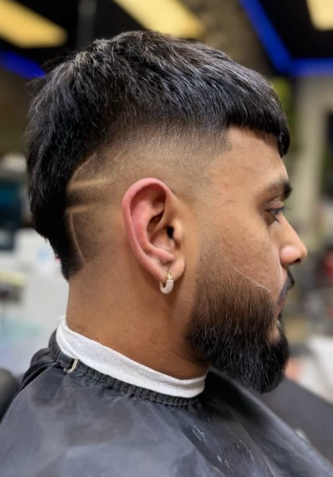 Mid fade with a razor-lined beard, side profile