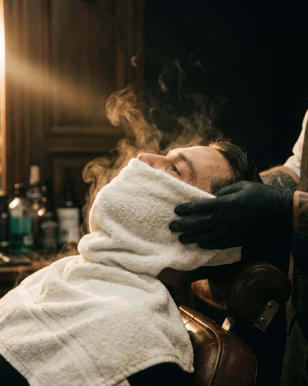 Steaming hot towel resting over a client's face in the chair